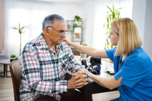 Elderly man receives emotional support from a caregiver during a home visit.