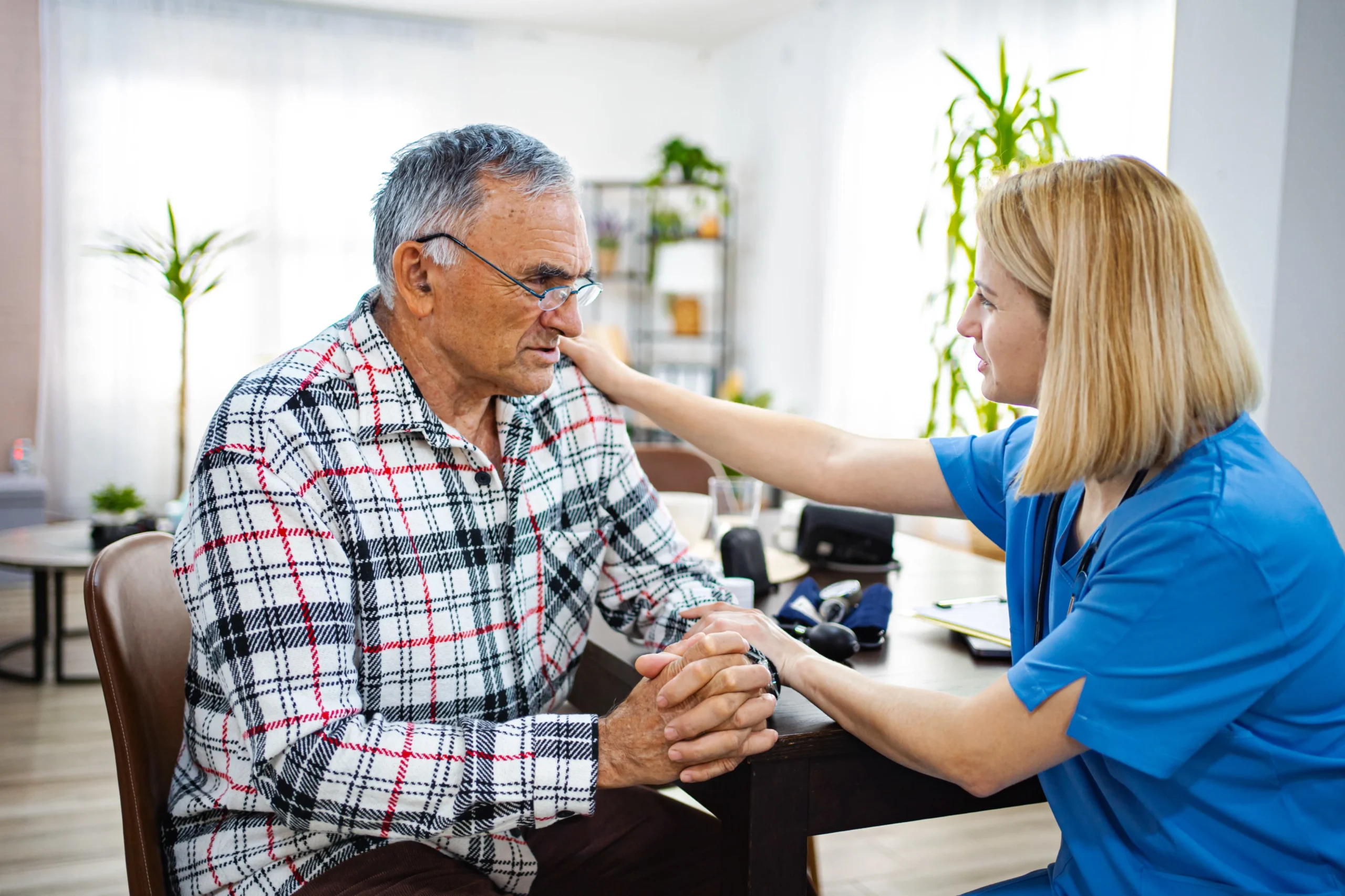 Elderly man receives emotional support from a caregiver during a home visit.