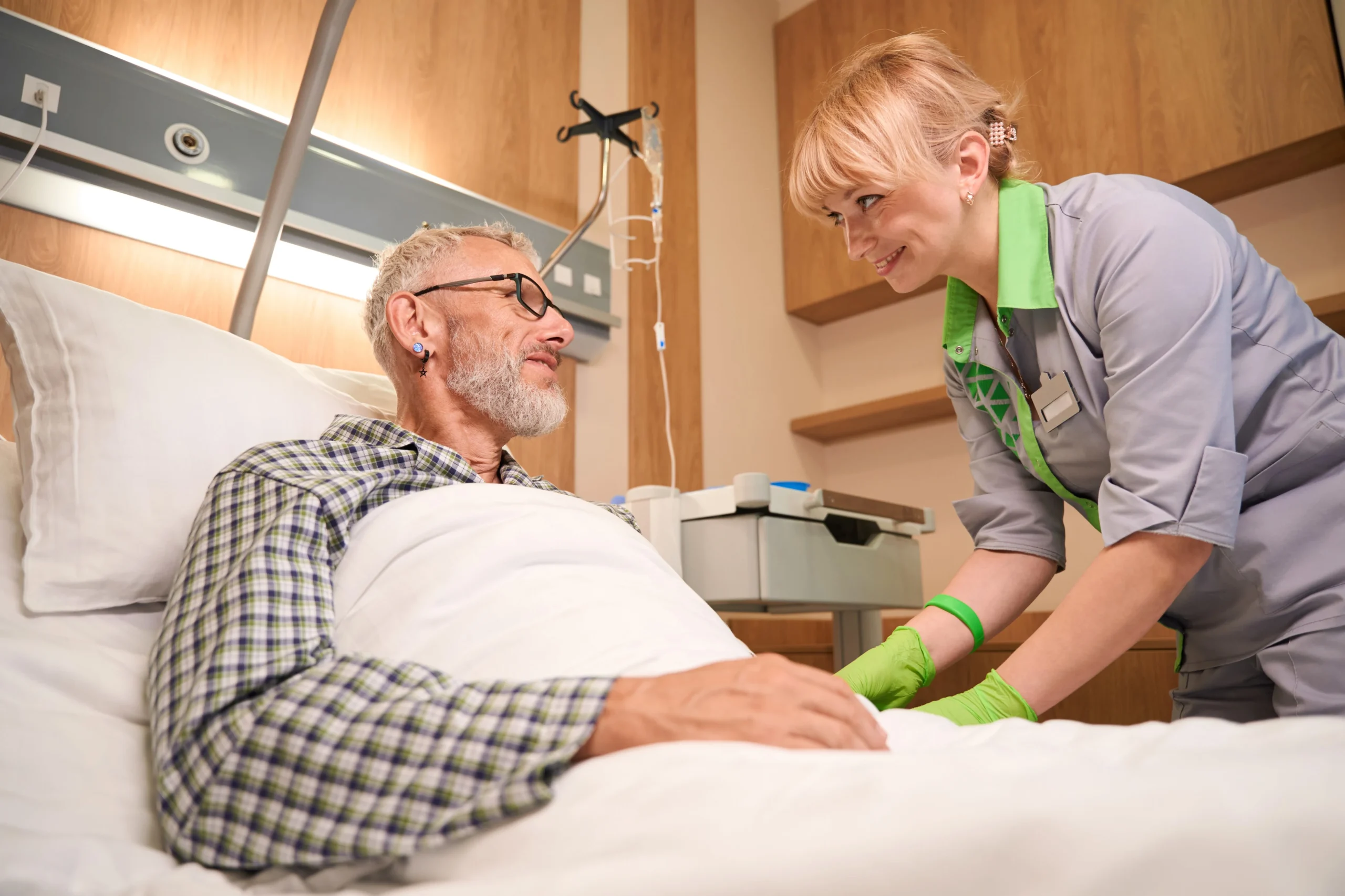 Nurse supporting elderly man during hospital care and recovery.